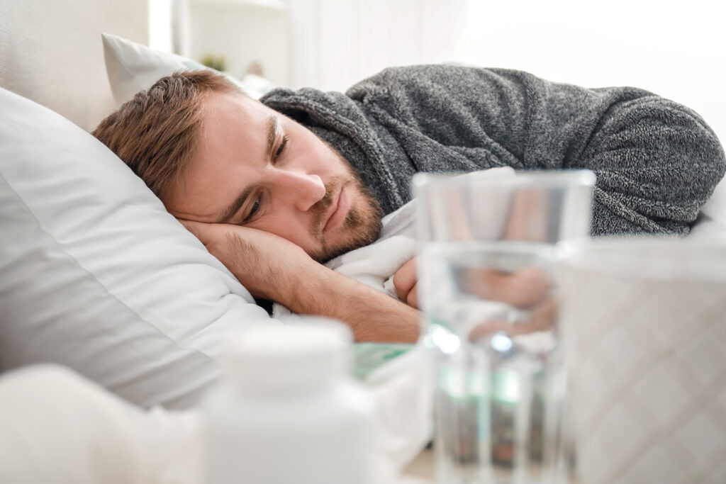 Man laying down with nearby water while undergoing alcohol withdrawal at home