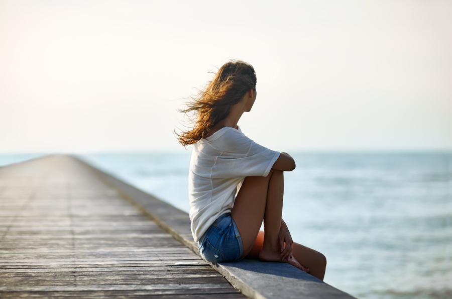 Profile picture of woman in cutoff shorts sitting on the edge of a dock on a lake