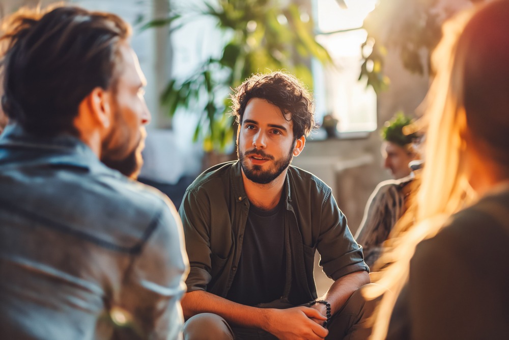 Man looks around in relief while talking to support group about managing addiction during the holidays