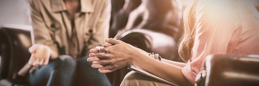 Close-up of woman clasping hands while participating in drug addiction support group