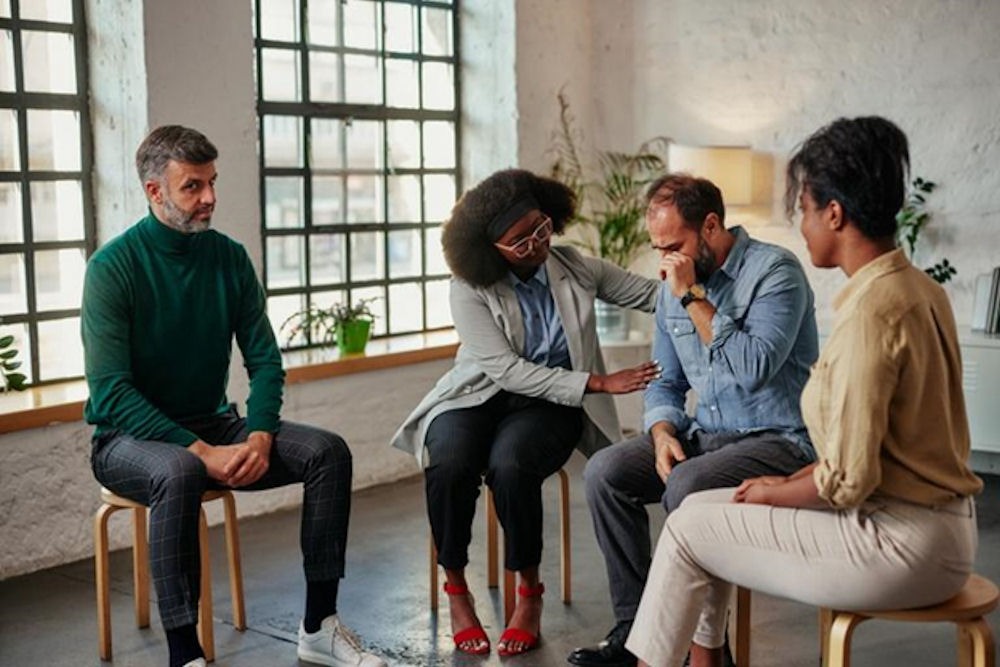 a man getting comfort from a woman during group therapy