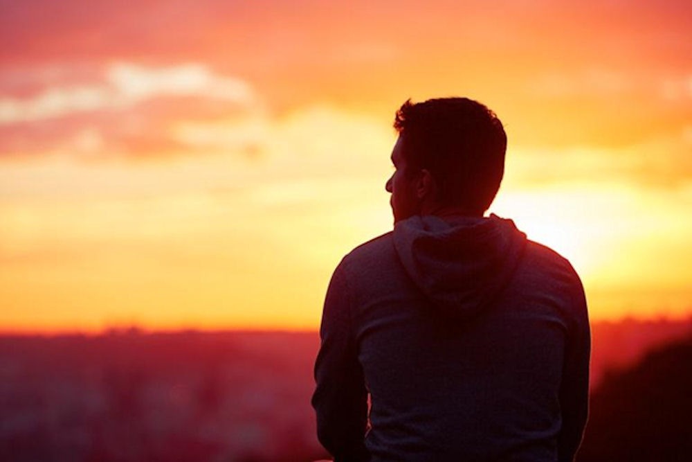 a man standing with sunset on background