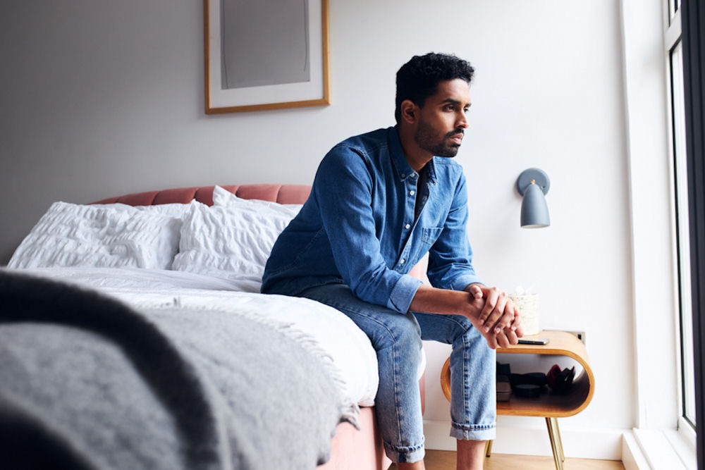 Man hunched over on edge of bed