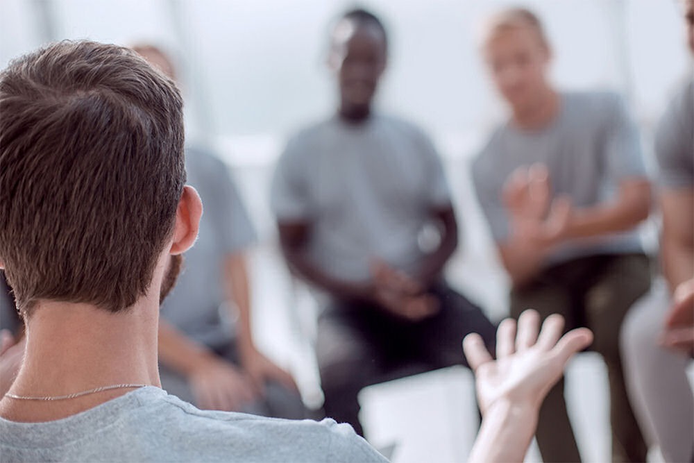 Man explaining dilated pupils to other members of a men's addiction recovery group